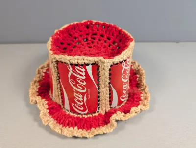 Sale Photo Thumbnail #226: Vintage handcrafted Coca-Cola can top hat pin cushion or novelty item, featuring crocheted red and beige yarn trim around cut aluminum soda cans.