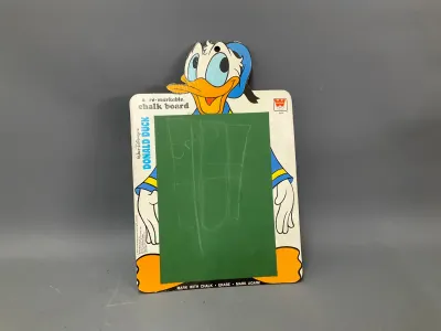 Sale Photo Thumbnail #346: Vintage Walt Disney's Donald Duck Whitman re-markable chalk board, featuring a die-cut character top and green chalkboard center with original chalk markings.