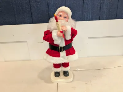 Sale Photo Thumbnail #477: Vintage animated Santa Claus figure holding an illuminated candle, featuring a classic red suit with white faux fur trim and gold-framed wire glasses.