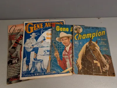 Sale Photo Thumbnail #291: Collection of vintage Gene Autry publications from the 1940s and 1950s, including Dell comic books and sheet music songbooks, showing visible wear and aging.