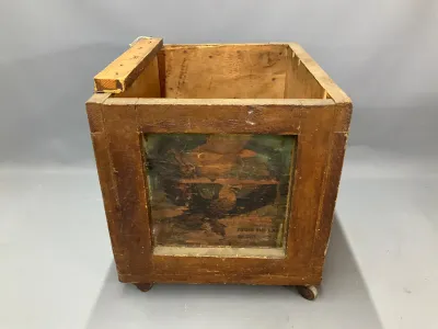 Sale Photo Thumbnail #154: Antique rustic wooden crate on casters, featuring a faded eagle graphic panel on the front and showing heavy wear consistent with age.