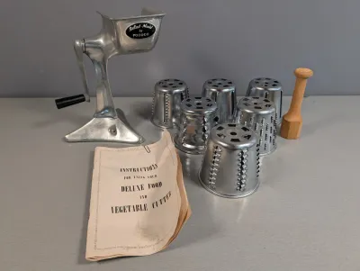 Sale Photo Thumbnail #367: Vintage Salad-Maid by Foodco aluminum manual food and vegetable cutter set. Includes hand-crank stand, five stainless steel cutting cones, wooden food pusher, and original instruction booklet.
