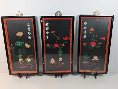 Sale Photo Thumbnail #125: Set of three vintage Chinese framed 3D stone and lacquer wall plaques featuring floral motifs and calligraphy, with minor wear to the black frames.