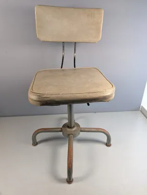 Sale Photo Thumbnail #34: Vintage industrial drafting stool with tan vinyl upholstery and a gray painted metal four-legged base.