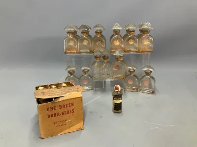 Sale Photo Thumbnail #157: Collection of vintage Dura-Gloss nail polish bottles with fan-shaped stoppers, accompanied by an original cardboard shipping box.