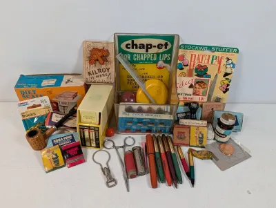 Sale Photo Thumbnail #108: Collection of mid-20th-century vintage ephemera and small collectibles, including a Chap-et counter display, writing utensils, matchbooks, a corn cob pipe, and medical tools.
