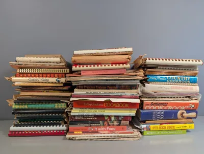 Sale Photo Thumbnail #285: Large stack of vintage and modern cookbooks and cooking booklets, including Betty Crocker's Cookbook and The Settlement Cookbook, showing varying degrees of edge wear and age.