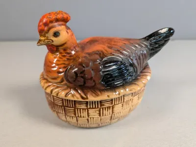 Sale Photo Thumbnail #173: Vintage ceramic hen-on-nest covered dish featuring a painted brown and black rooster lid resting on a basketweave base.