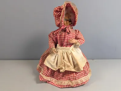 Sale Photo Thumbnail #213: Vintage character doll featuring an elderly woman with glasses, dressed in a red and white gingham dress, bonnet, and white apron.