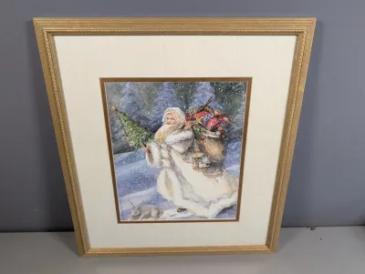 Sale Photo Thumbnail #437: Framed winter art print featuring Santa Claus carrying a tree and sack of toys in the snow, set in a metallic gold frame with double matting.