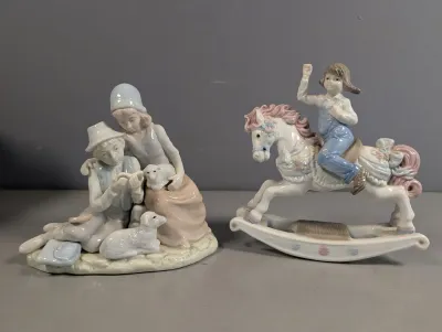 Sale Photo Thumbnail #39: Two porcelain figurines featuring subtle pastel colors, including a shepherd couple with lambs and a child riding a rocking horse.