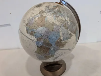 Sale Photo Thumbnail #482: Vintage desk globe with a metal semi-meridian and stand, featuring political boundaries in parchment-style tones.