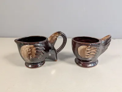 Sale Photo Thumbnail #185: Vintage ceramic rooster cream and sugar set with a glossy dark brown glaze and raised feather details.