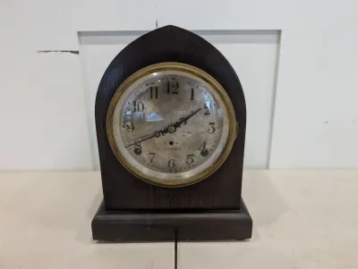Sale Photo Thumbnail #481: Antique Seth Thomas gothic arched mantel clock in a dark wood case, featuring a brass-bezeled silvered dial with Arabic numerals.