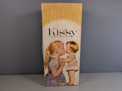 Sale Photo Thumbnail #223: Vintage Ideal 'Kissy The New Kissing Doll' original box from 1961, showing moderate edge wear and aging.