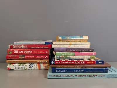 Sale Photo Thumbnail #283: Two stacks of assorted hardcover and paperback books covering self-help, health, biography, and history topics.