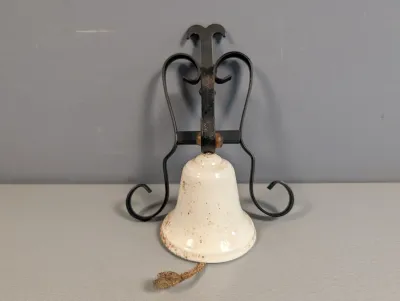 Sale Photo Thumbnail #277: Vintage white enamel cast iron dinner bell mounted on a black scrollwork wrought iron bracket.
