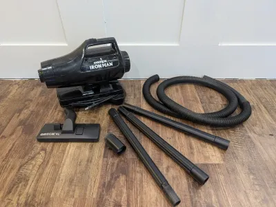 Sale Photo Thumbnail #475: Black Oreck Ironman canister vacuum cleaner with hose, extension wands, floor nozzle, and brush attachment.