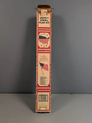 Sale Photo Thumbnail #427: Vintage United States flag kit in its original cardboard box, featuring a 3x5-foot flag, three-piece pole, gold eagle, and mounting bracket.