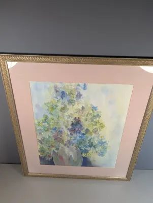 Sale Photo Thumbnail #466: Framed floral watercolor painting under glass, featuring pastelhydrangeas in a vase with a dusty rose mat and textured metallic frame.