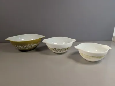 Sale Photo Thumbnail #46: Set of three vintage Pyrex Cinderella mixing bowls featuring olive green floral and geometric patterns, including Spring Blossom and Butterfly Gold, circa 1970s.