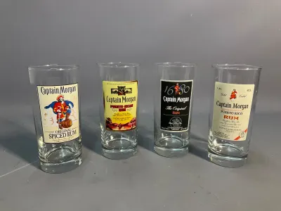 Sale Photo Thumbnail #86: Set of four vintage Captain Morgan rum highball glasses featuring distinct printed bottle label graphics.
