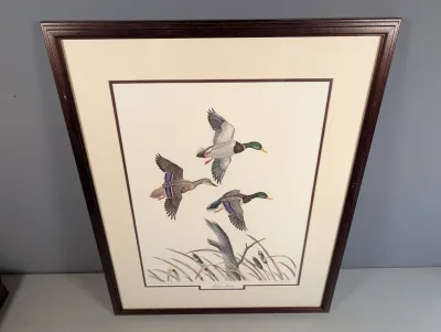 Sale Photo Thumbnail #19: Framed wildlife art print titled "Autumn Pattern," depicting mallard ducks in flight over a marshland setting, double-matted in a dark wood frame.