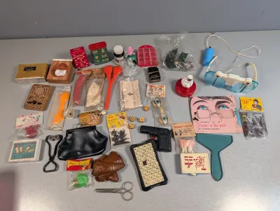 Sale Photo Thumbnail #216: Collection of vintage gag gifts, novelties, and small toys including fake teeth, magic tricks, prank items, and plastic novelties.