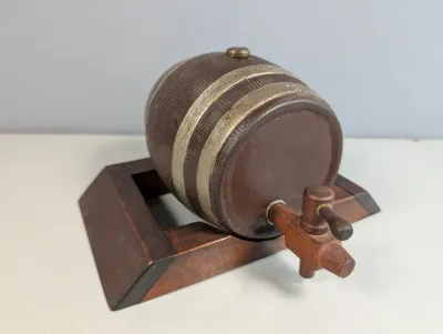 Sale Photo Thumbnail #186: Vintage miniature wooden liquor barrel dispenser on a matching wooden stand, featuring metal hoops and a spigot.