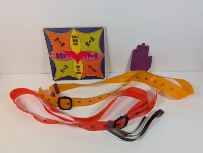 Sale Photo Thumbnail #121: Vintage Milton Bradley Feet-It game pieces, including colorful spinner board, vinyl straps with buckles, and a purple hand marker.