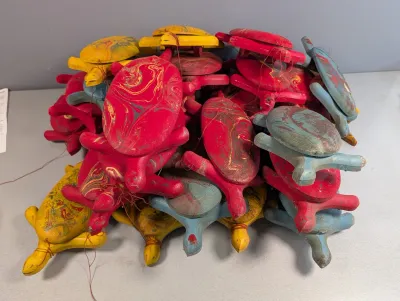 Sale Photo Thumbnail #204: Large collection of hand-carved wooden sea turtle ornaments painted in marbled shades of red, yellow, and blue.