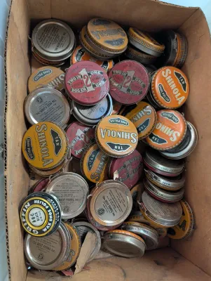 Sale Photo Thumbnail #246: Cardboard box filled with vintage shoe polish tins, including Shinola, 2 in 1, and Griffin brands.