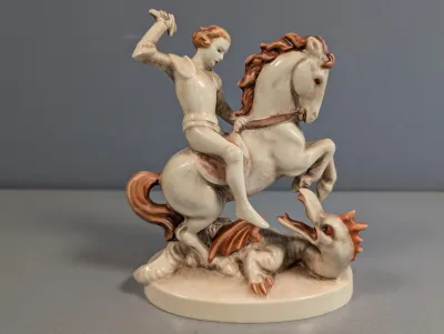 Sale Photo Thumbnail #426: Vintage ceramic figurine depicting Saint George slaying the dragon, featuring hand-painted reddish-brown and off-white details.