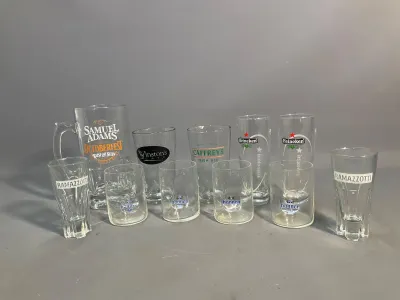Sale Photo Thumbnail #58: Collection of assorted branded glassware and barware, including a Samuel Adams glass pitcher, Heineken pilsner glasses, Hannen Alt tumblers, and Ramazzotti digestif glasses.