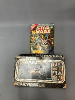 Sale Photo Thumbnail #366: Vintage 1977 Kenner Star Wars Escape From Death Star board game in original box alongside a Marvel Special Edition Star Wars Treasury comic book, both showing age-appropriate shelf wear.