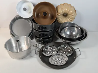 Sale Photo Thumbnail #499: Collection of assorted bakeware including tube pans, springform pans, round cake tins, a ceramic bundt mold, mixing bowls, and specialized poaching inserts.