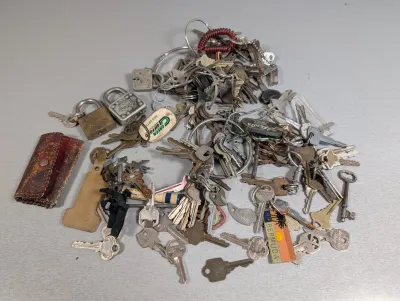 Sale Photo Thumbnail #433: Large collection of vintage keys, keychains, small padlocks, and a worn leather key pouch.
