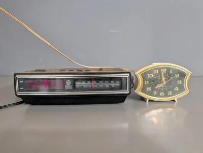 Sale Photo Thumbnail #259: Vintage General Electric digital alarm clock radio alongside a vintage GE Snooz-Alarm tabletop clock.