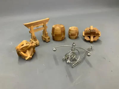 Sale Photo Thumbnail #344: Collection of vintage mechanical brain teaser puzzles, including Japanese wooden interlocking burr puzzles and a metal wire puzzle.