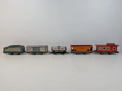 Sale Photo Thumbnail #116: Vintage Unique Lines lithographed tinplate toy train car set, including a tender, boxcar, tanker car, hopper, and caboose, circa 1940s-1950s.