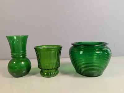 Sale Photo Thumbnail #205: Set of three vintage green glassware pieces, including a small flared vase, a ribbed goblet-style votive holder, and a round ribbed bowl.