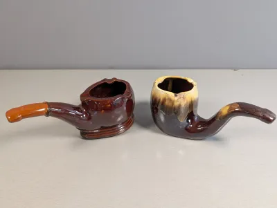 Sale Photo Thumbnail #172: Pair of vintage glazed ceramic pipe-shaped novelty ashtrays in brown and drip-glaze finishes.