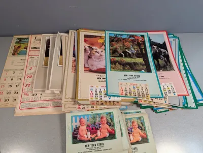 Sale Photo Thumbnail #237: Large collection of vintage advertising wall calendars, featuring various imagery including animals, landscapes, and babies.