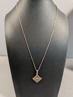 Sale Photo Thumbnail #5: Sterling silver chain necklace featuring a diamond-shaped filigree pendant with a central green gemstone.