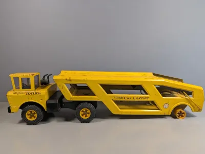 Sale Photo Thumbnail #379: Vintage yellow pressed steel Mighty Tonka Car Carrier truck, featuring played-with condition with paint wear and missing rear trailer wheels.