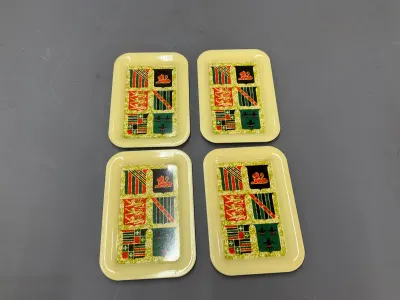 Sale Photo Thumbnail #330: Set of four vintage yellow composite snack trays featuring heraldic crest motifs, in good condition.