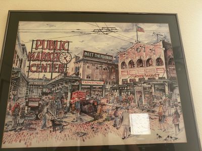 Sale Photo Thumbnail #71: Framed artwork depicting Seattle's Pike Place Market, signed by artist Clementson and dated 1986. Presented in a black frame with a dark double mat.