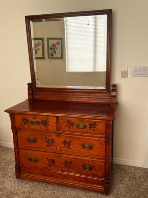 Sale Photo Thumbnail #29: Antique wooden dresser featuring carved floral accents, brass bail pulls, and a large attachable mirror.