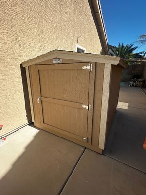 Sale Photo Thumbnail #62: Small Tuff Shed outdoor storage unit painted beige with white trim, featuring a single front door and pitched roof.