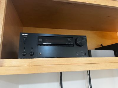 Sale Photo Thumbnail #44: Onkyo AV receiver in a black finish, model TX-NR757, sitting on a wooden shelf.